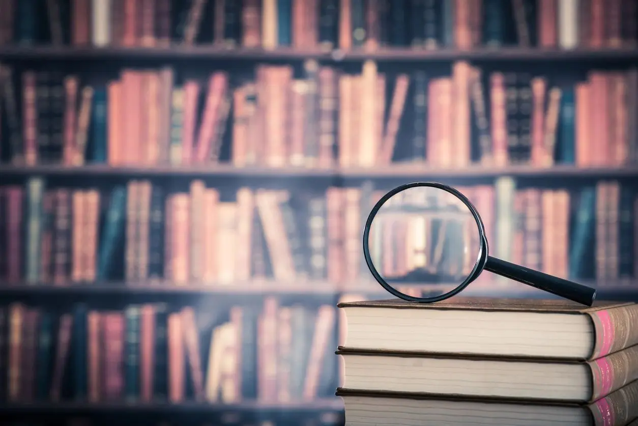 A magnifying glass sitting on top of books.